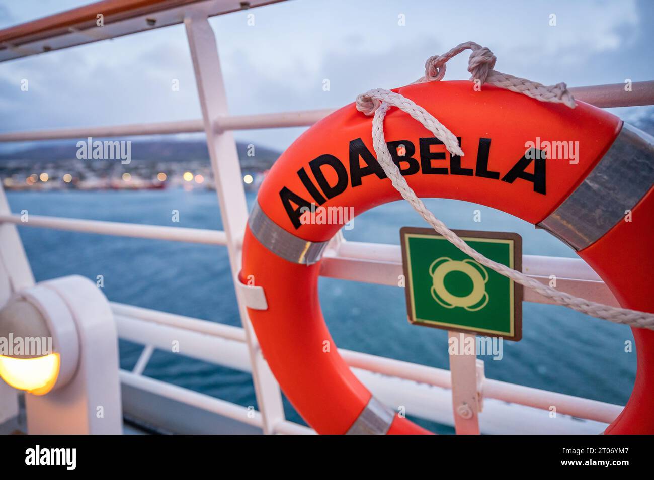 Close-up orange lifebuoy of AIDA Bella cruise ship attached to ship railing in the evening with city of Iceland in the background Stock Photo