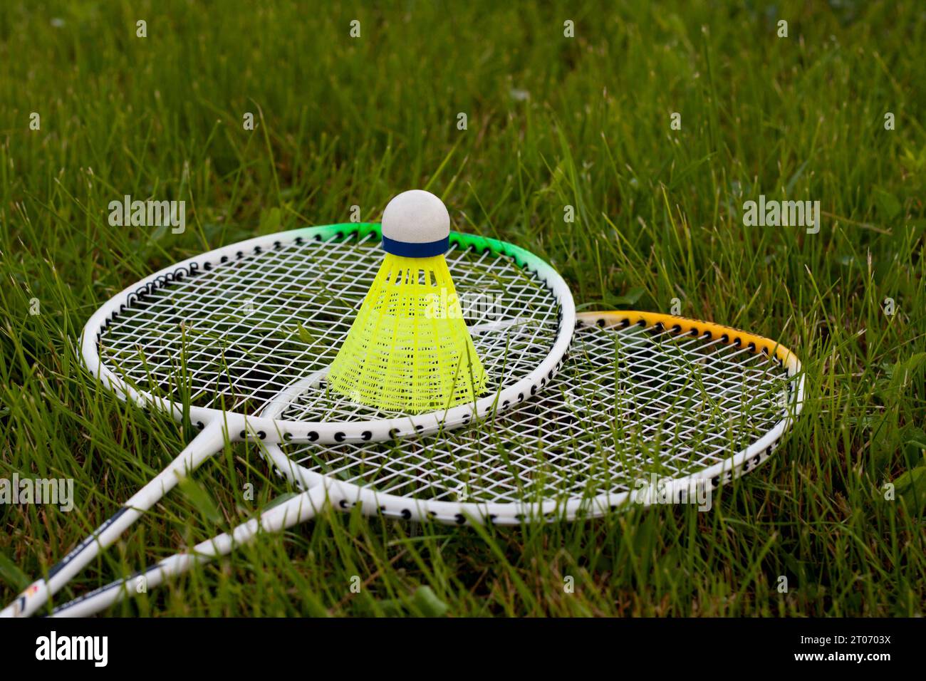 Badminton set yellow shuttlecock and rackets lying on green grass. Sports concept. Active game of badminton outdoors. Sport equipment. Stock Photo