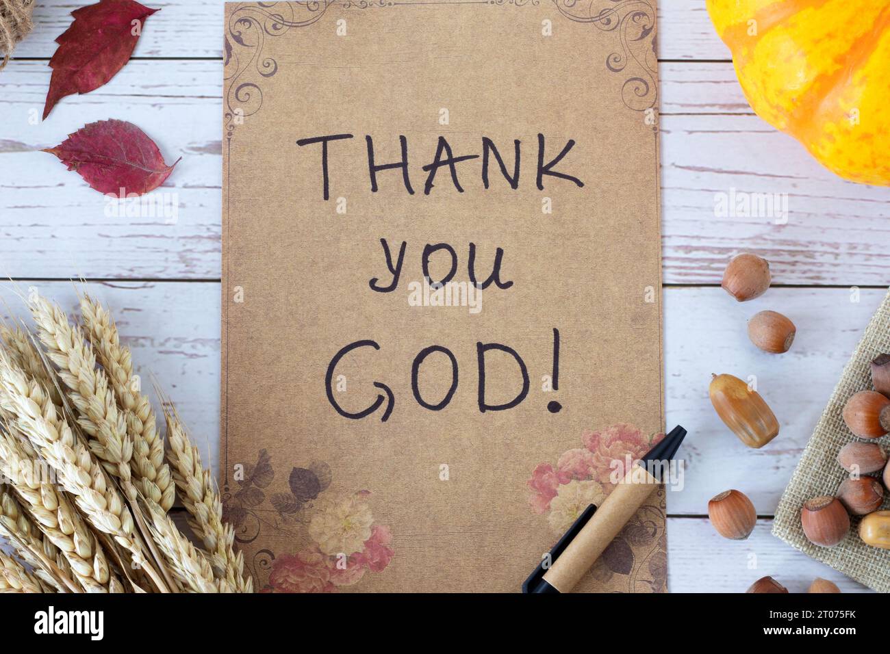 Thank You God, handwritten message on vintage paper with autumn leaves, pumpkin, and wheat on wood. Top view. Christian thanksgiving to Jesus Christ. Stock Photo