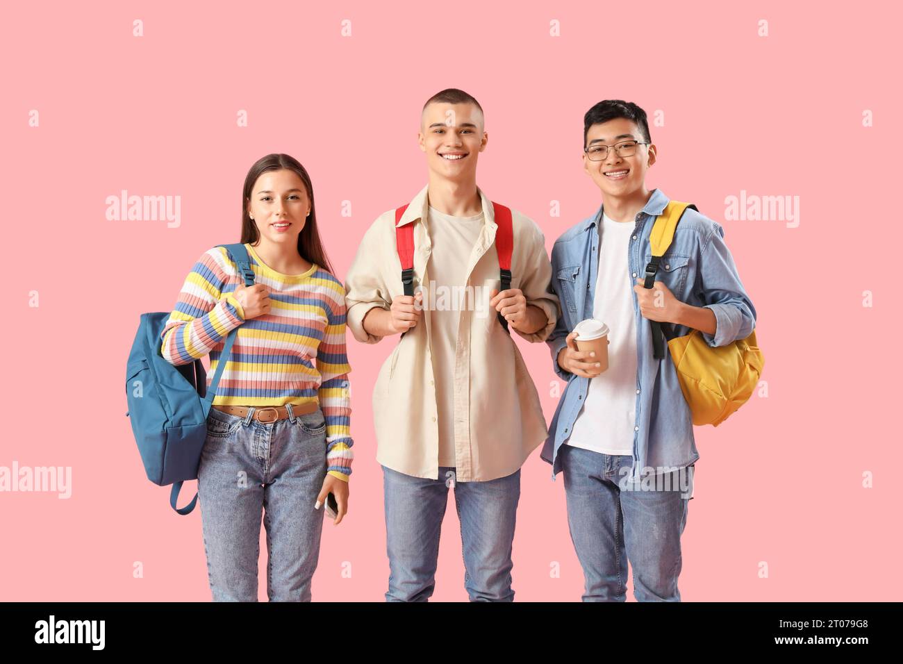 Happy students with backpacks and cup of coffee on pink background ...