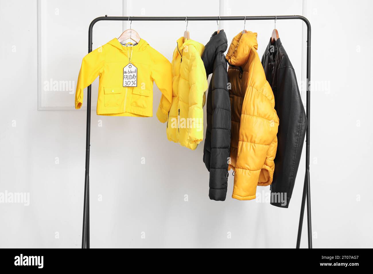 Rack with different jackets against light wall. Black Friday sale Stock Photo