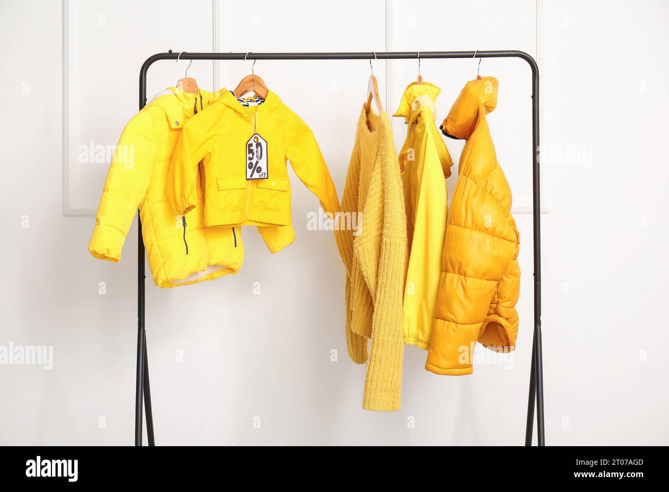 Rack with colorful clothes against light wall. Black Friday sale Stock Photo
