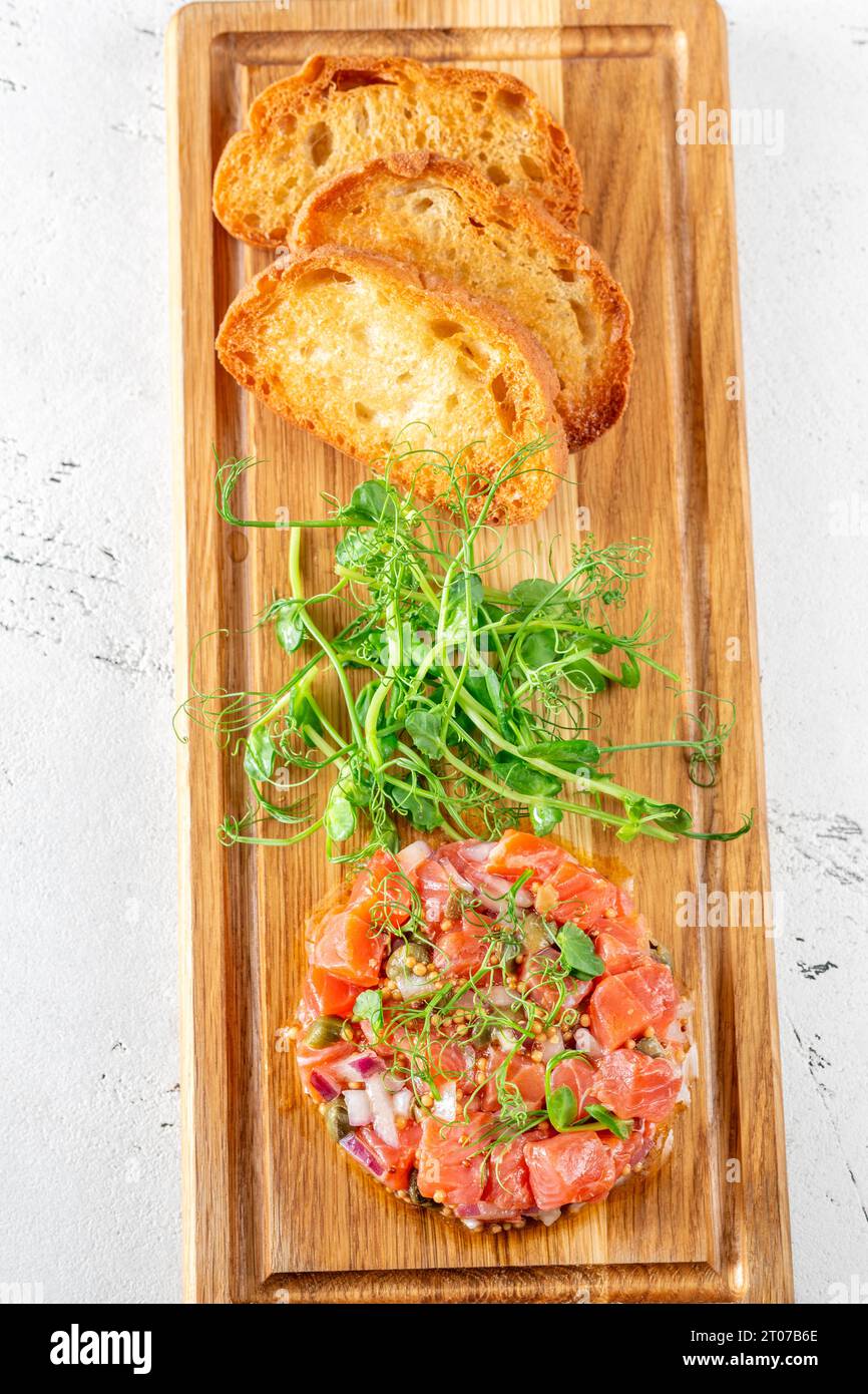 Portion of salmon tartare with bread and microgreen Stock Photo