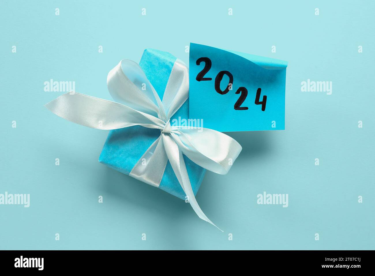 Sticky note with year 2024 and gift box on blue background Stock Photo