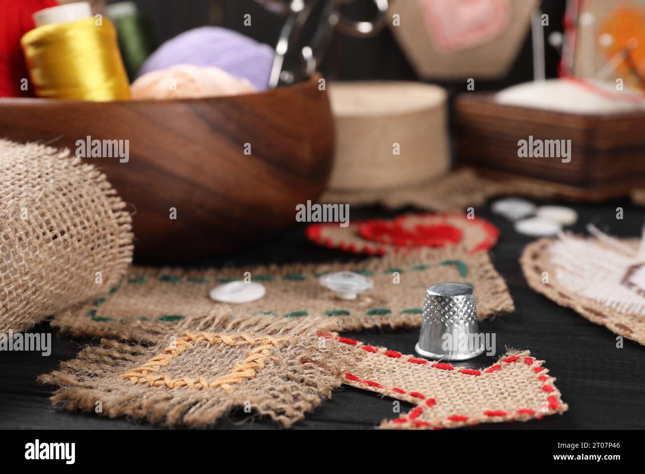 Pieces of burlap fabric with different stitches and thimble on black
