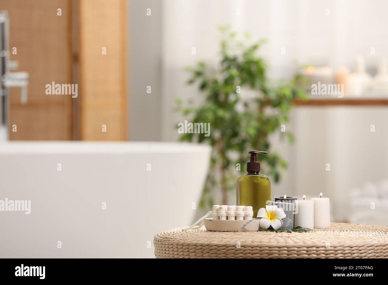 Spa products, burning candles and plumeria flower on wicker table in ...