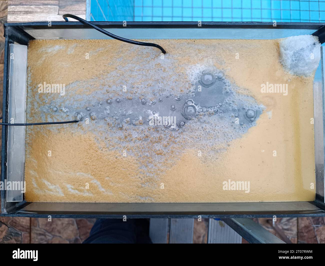 water surface in aquarium with bubbles and rust due to an experiment electrolysis process to