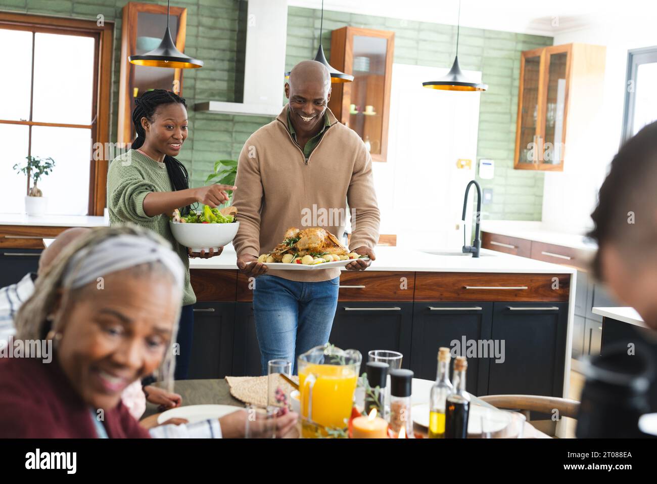 Happy african american mother and father serving food at thanksgiving