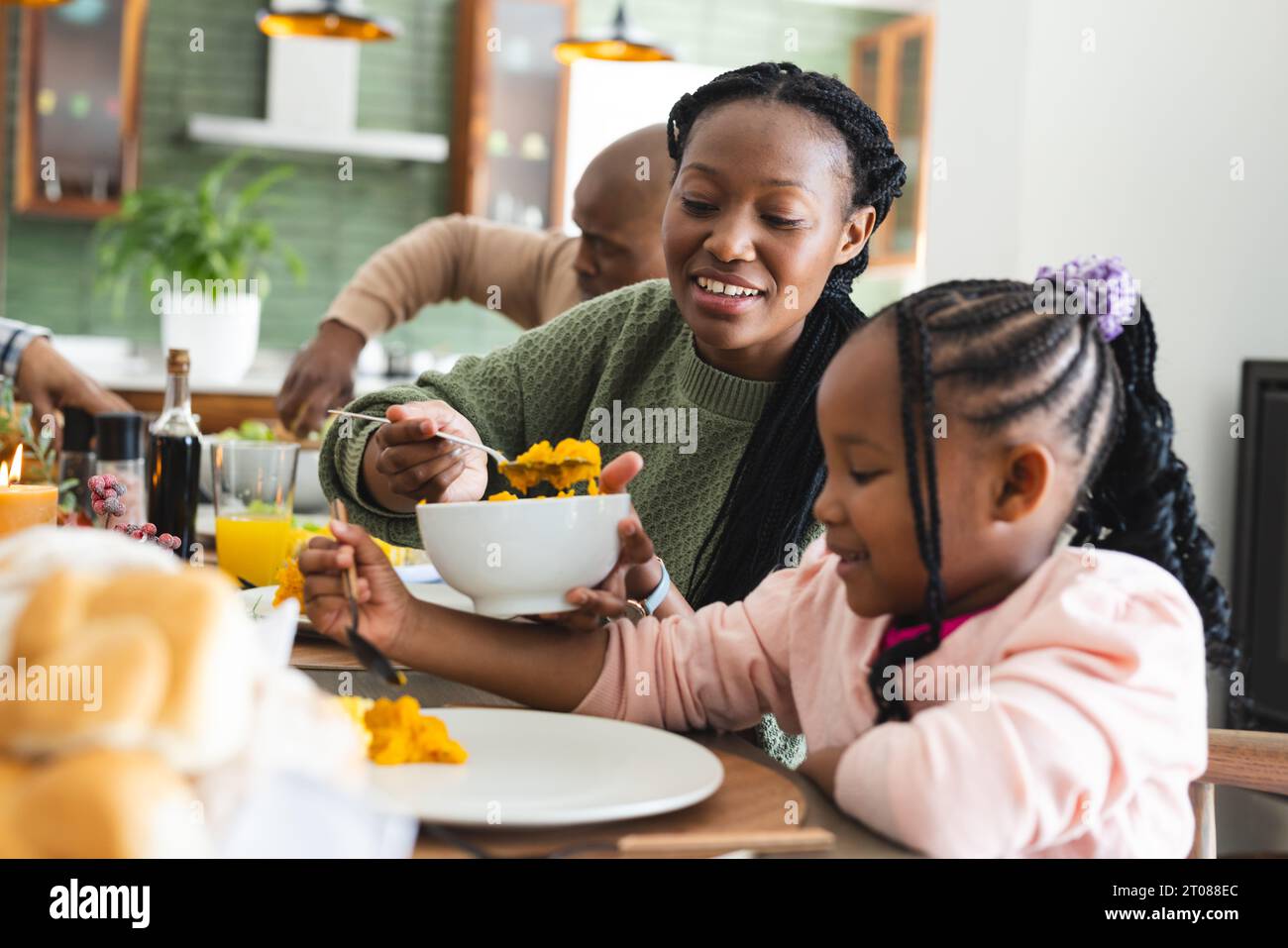 Happy african american mother serving food for daughter at thanksgiving ...