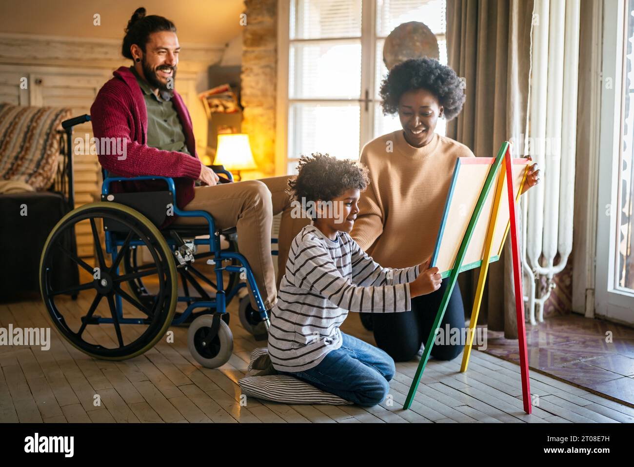 Happy multiethnic family with disability. Father in wheelchair enjoying time together with his son Stock Photo