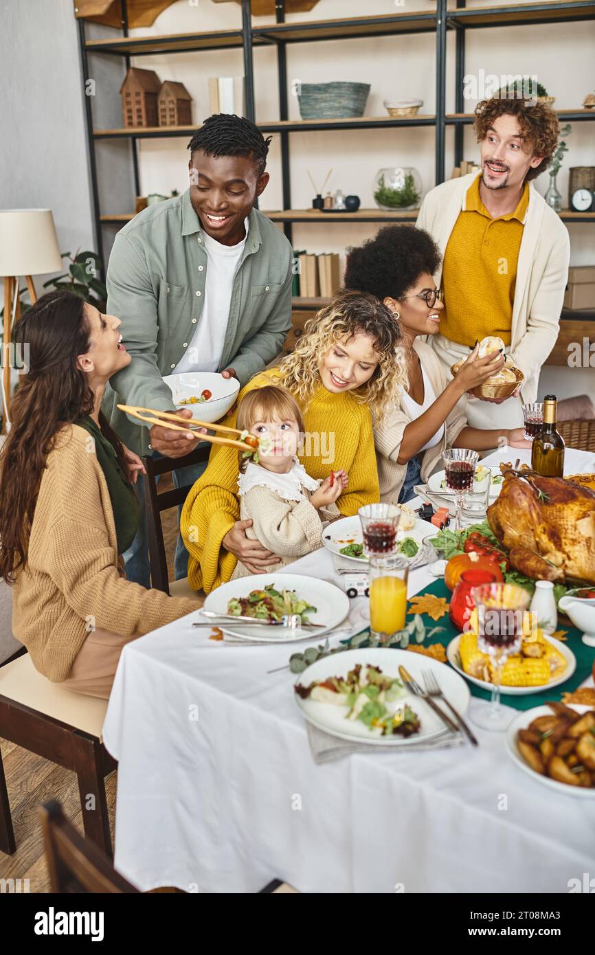 Happy Thanksgiving, cheerful multiethnic friends and family gathering at festive table with turkey Stock Photo
