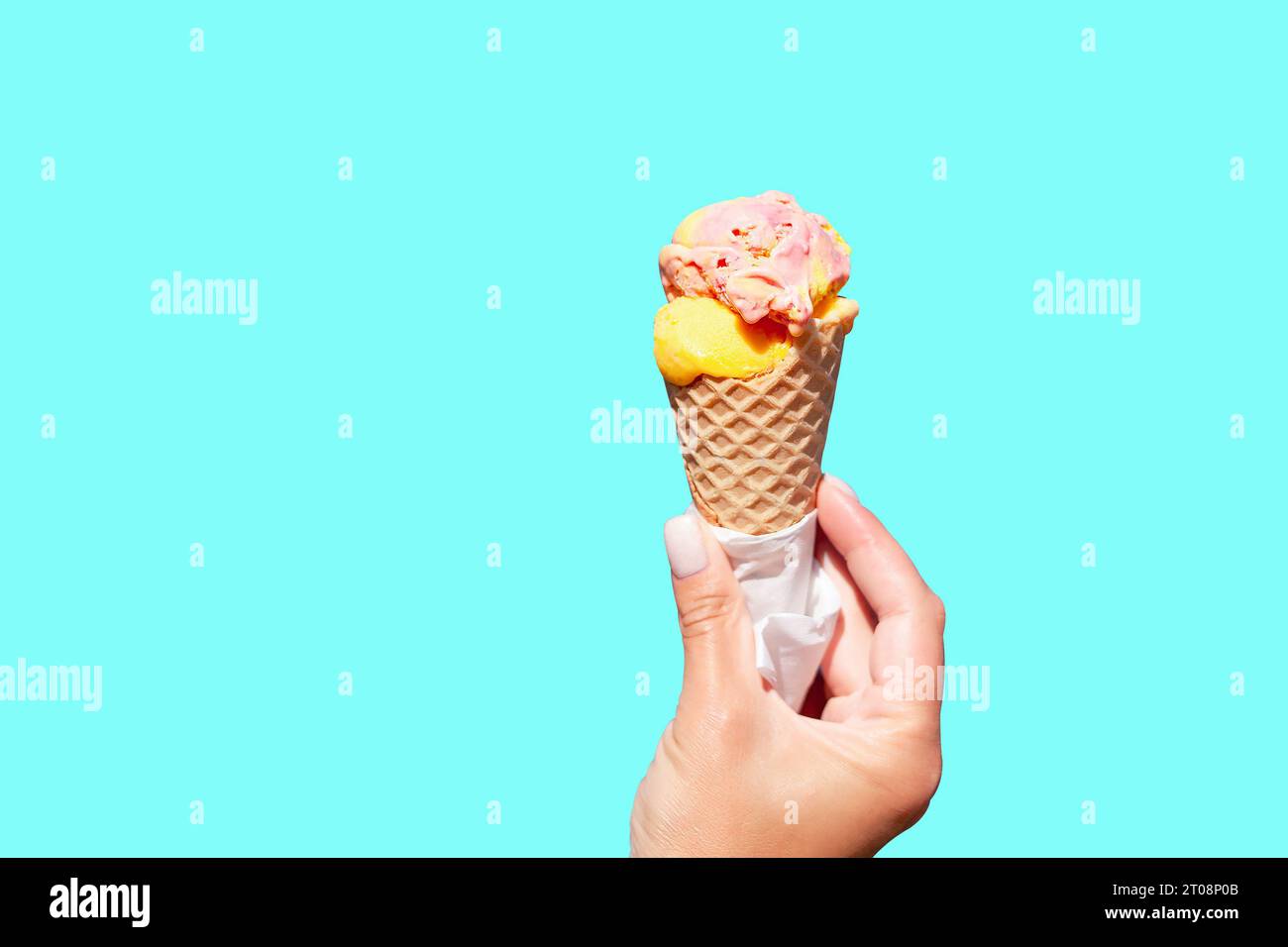 Ice cream cone in the hand against blue background. Female hand holding ...
