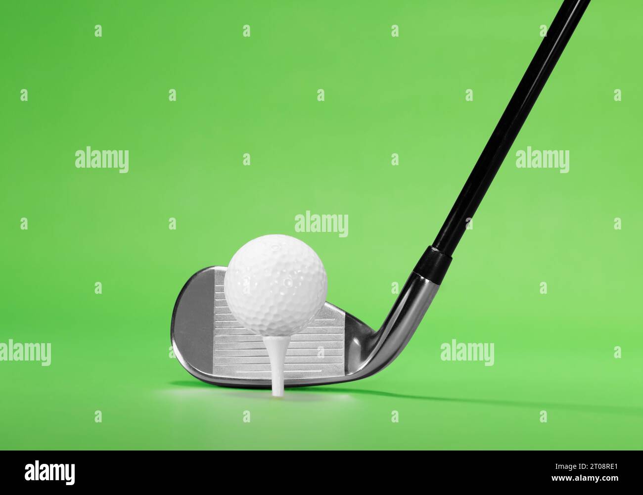 Golf Fairway Iron with a Golf Ball on White Tea, isolated on a Green Background Stock Photo