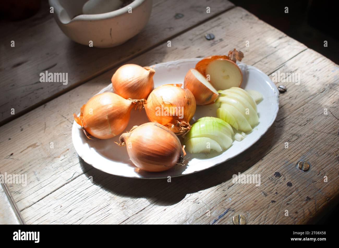Roughly cut onions on a victorian table top - John Gollop Stock Photo