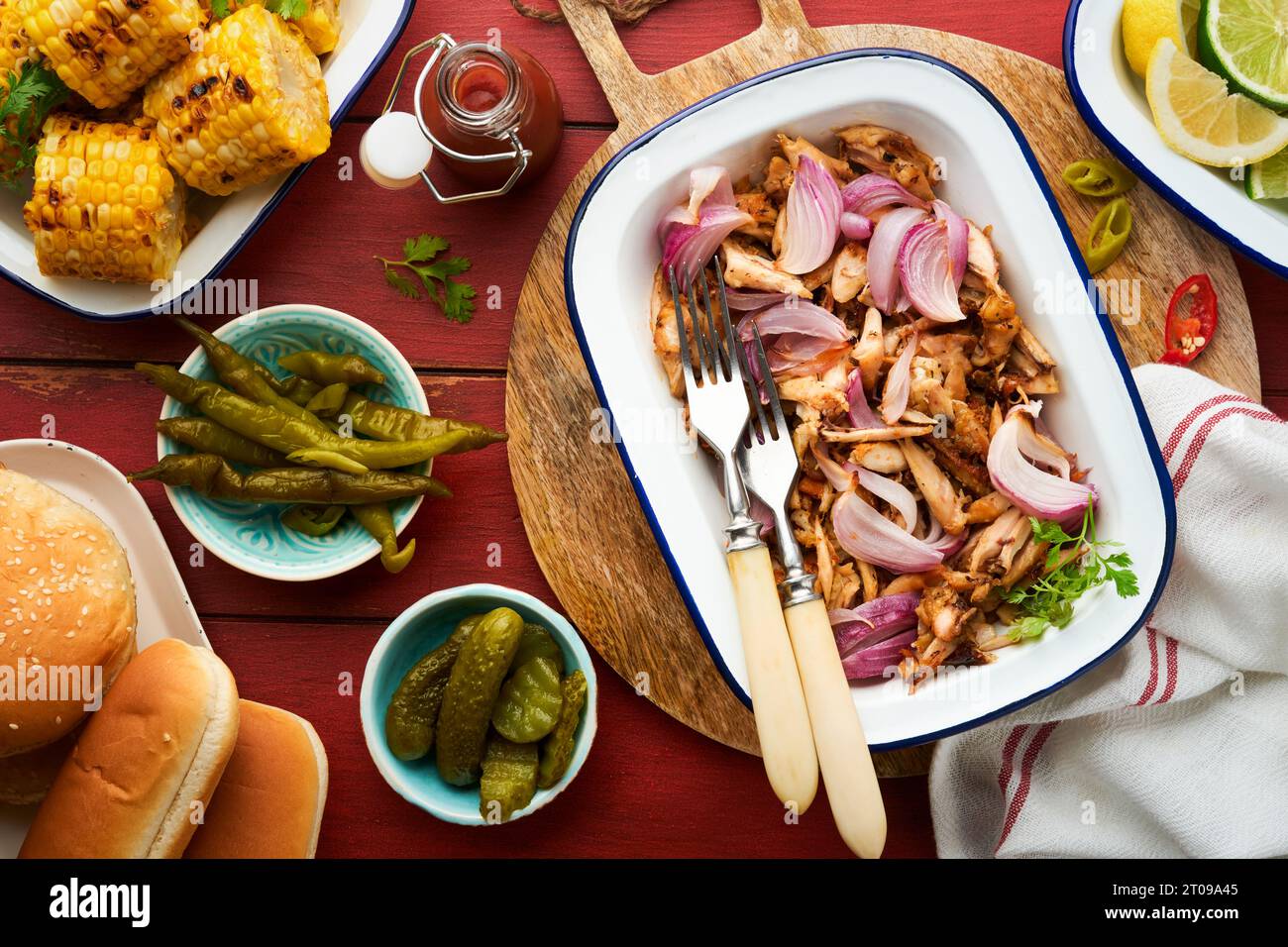 Pulled bbq chicken with baked onions on serving platter, bbq corn
