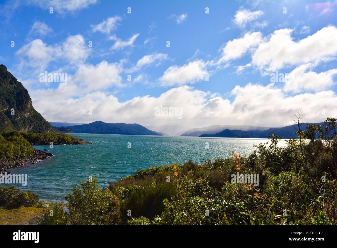 Beautiful Bay in New Zealand. Blue water and mountains in the back. Green nature. Stock Photo