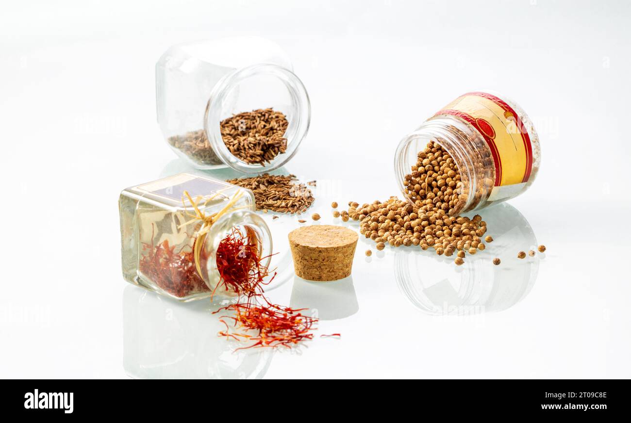 Jars with spices cumin, coriander and saffron on a glass background