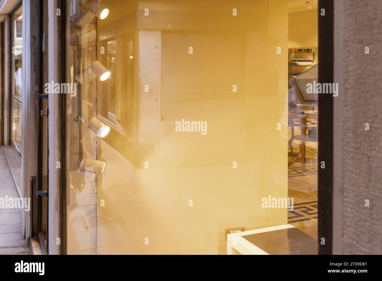 Shop window with a clear glass surface for logo or text prtesentation. View of the well lit interior, warm glow Stock Photo