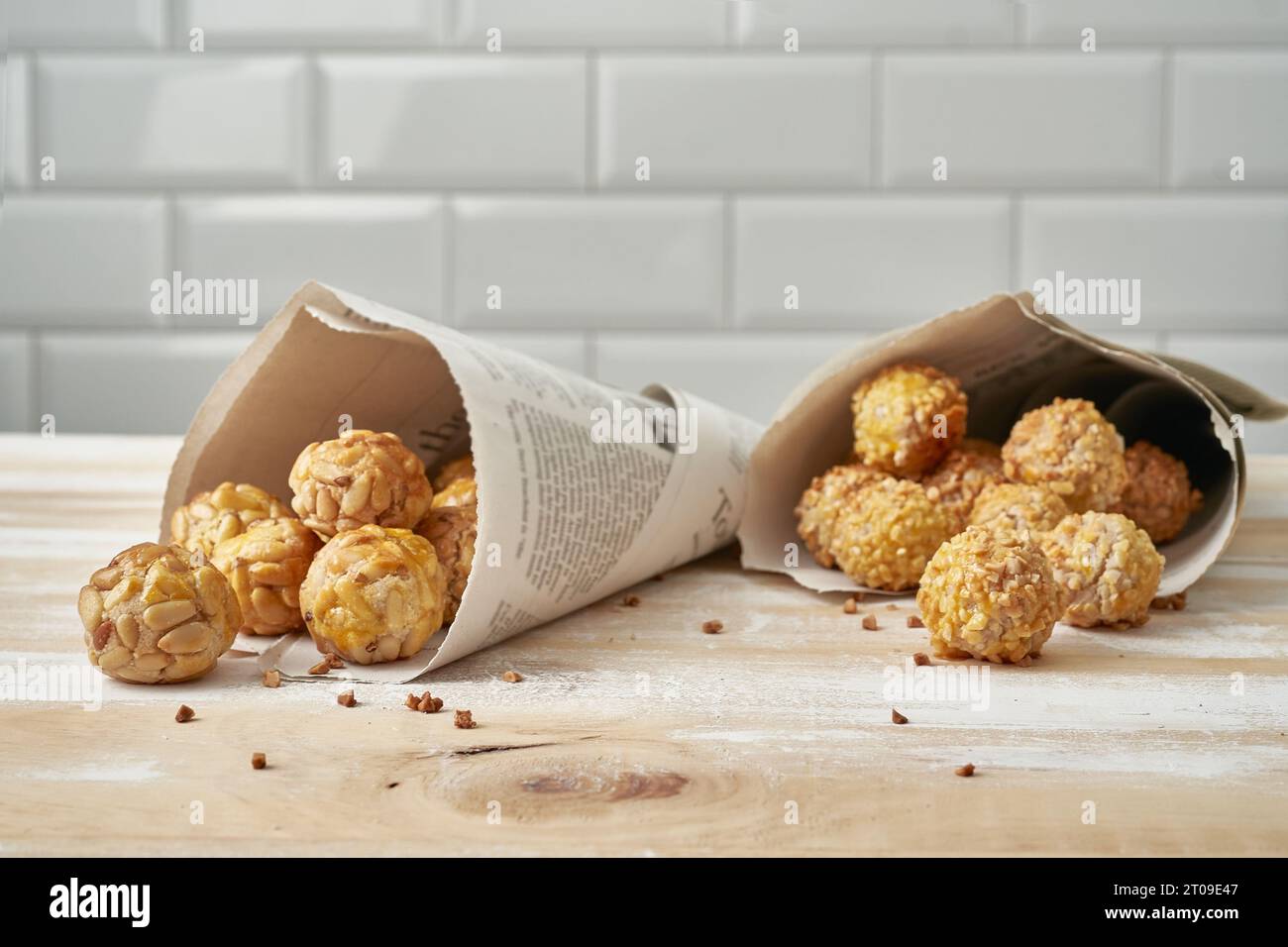Sweet panellets in newsprint cones placed on wooden table against white ...