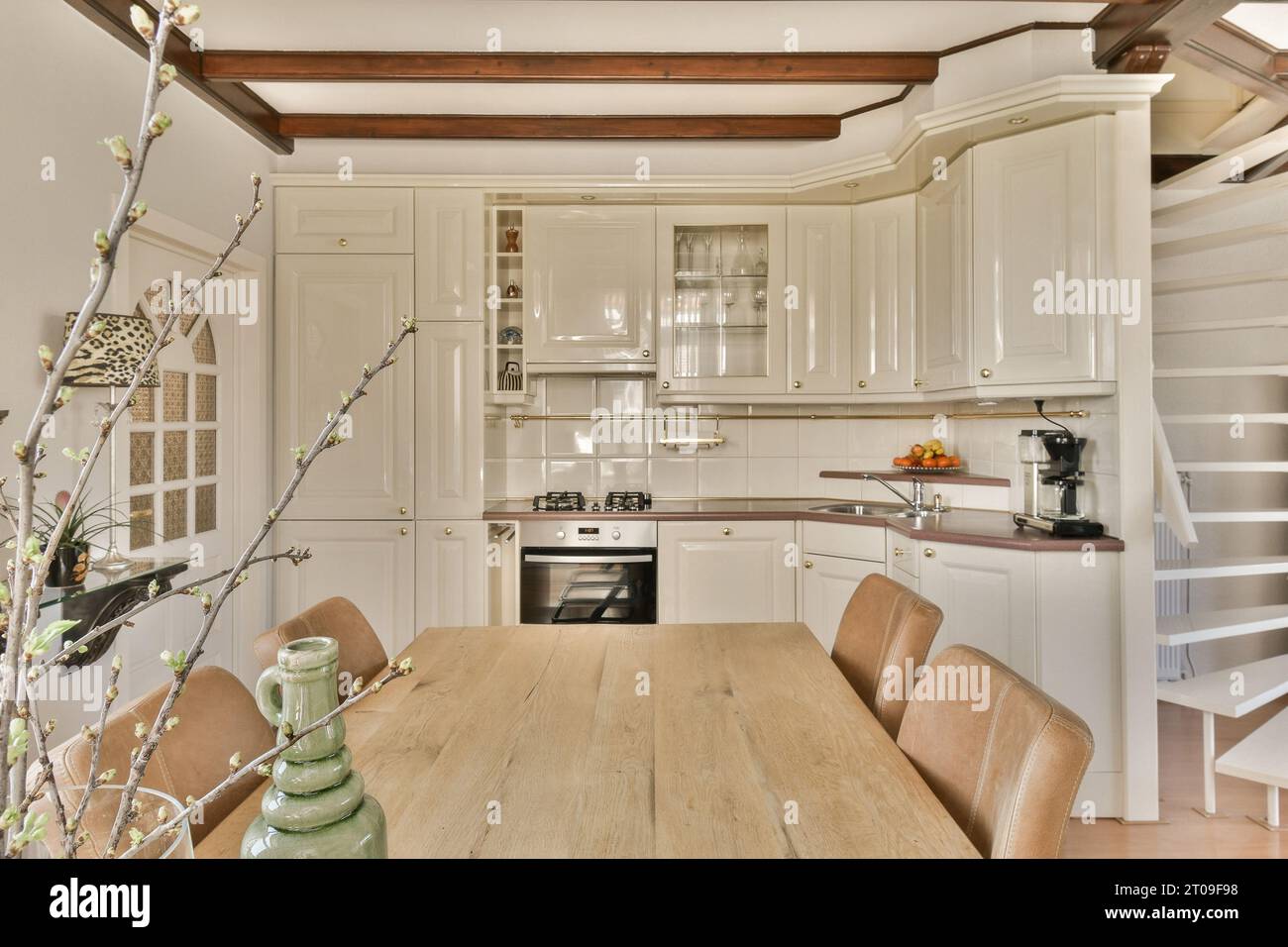 Interior of open plan kitchen with white cabinets and wooden dining ...