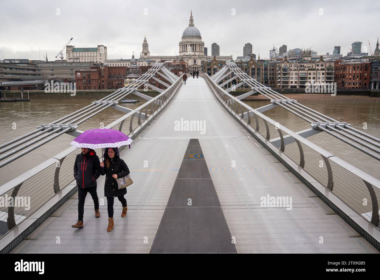 File photo dated 3/2/2021 of two people shelter under an umbrella as they cross a near deserted Millennium Bridge near St Paul's Cathedral, in central London. The Millennium Bridge across the River Thames is to shut for three weeks for urgent maintenance work. The footbridge, dubbed the 'wobbly bridge' when it opened in 2001, is not dangerous but a separation layer under the bridge deck has started to degrade and it needs a deep clean, its City Bridge Foundation (CBF) owners said. Issue date: Thursday October 5, 2023. Stock Photo