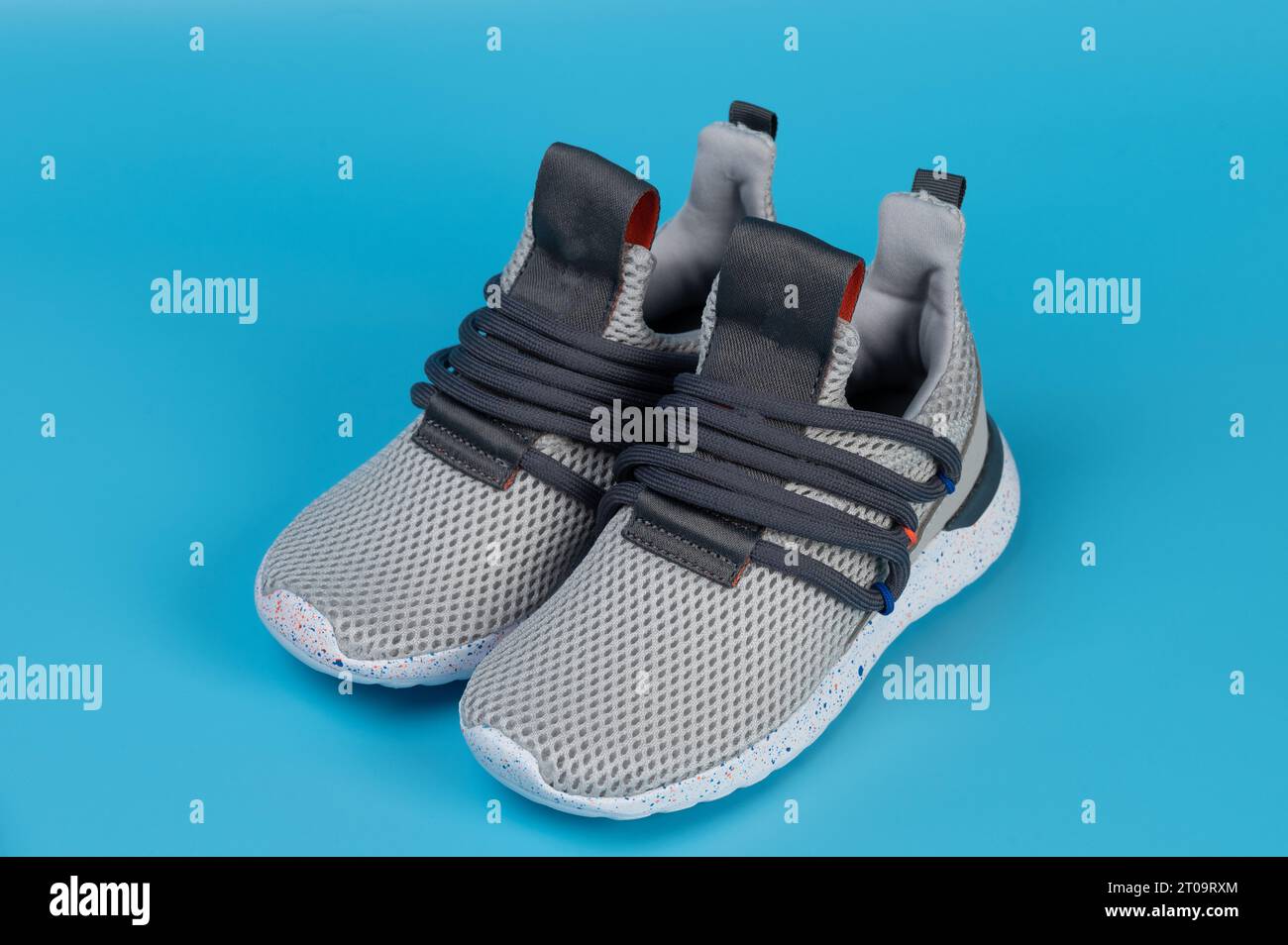 Grey laceless pair kid sport shoes perspective view isolated on blue studio background Stock Photo