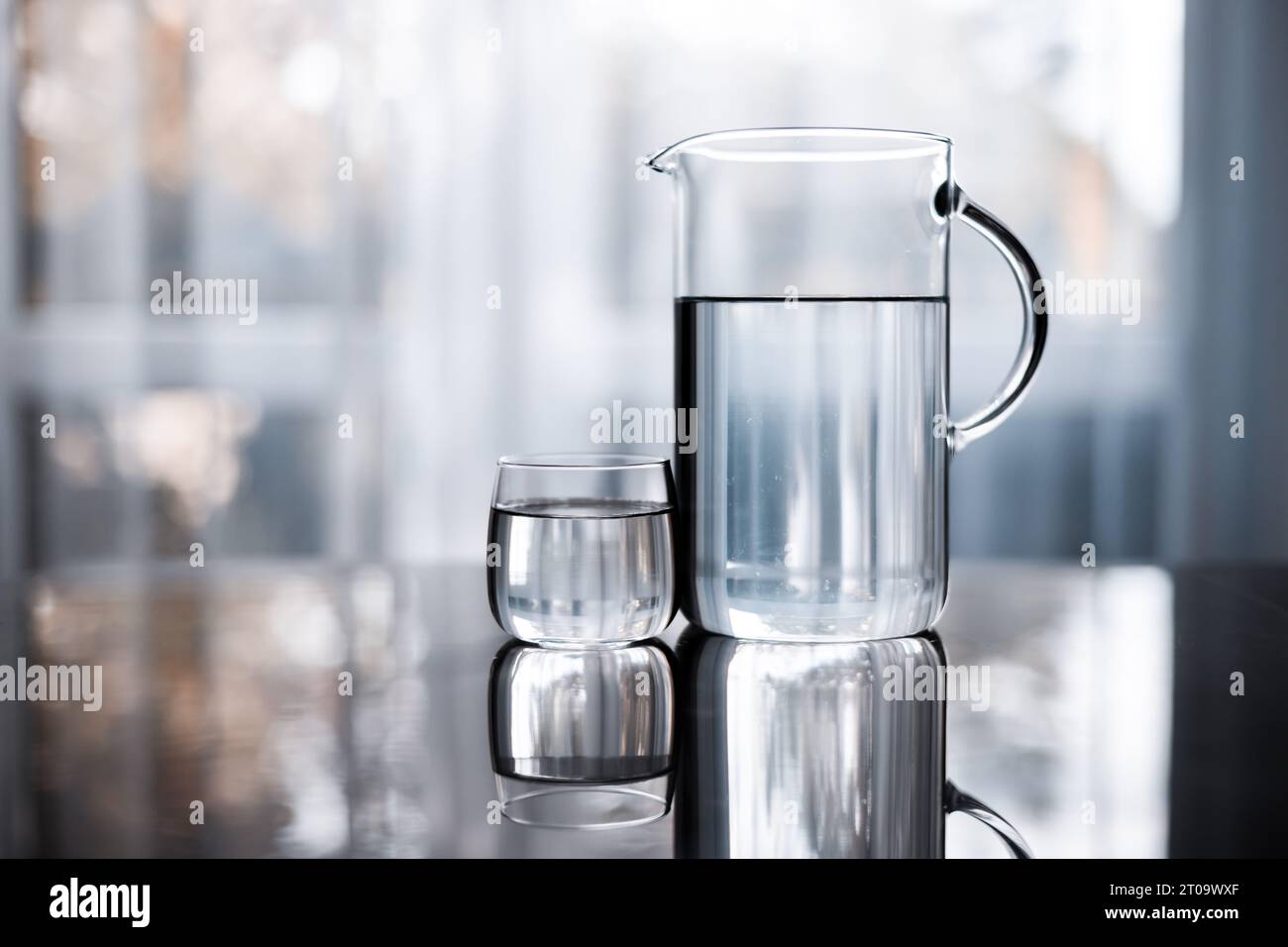 Decanter and glass of water on table on window background Stock Photo