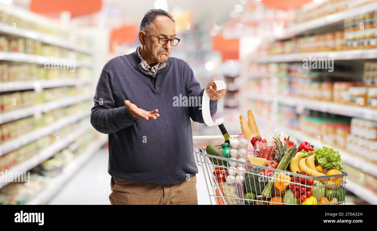 Confused mature man in a supermarket holding a bill Stock Photo