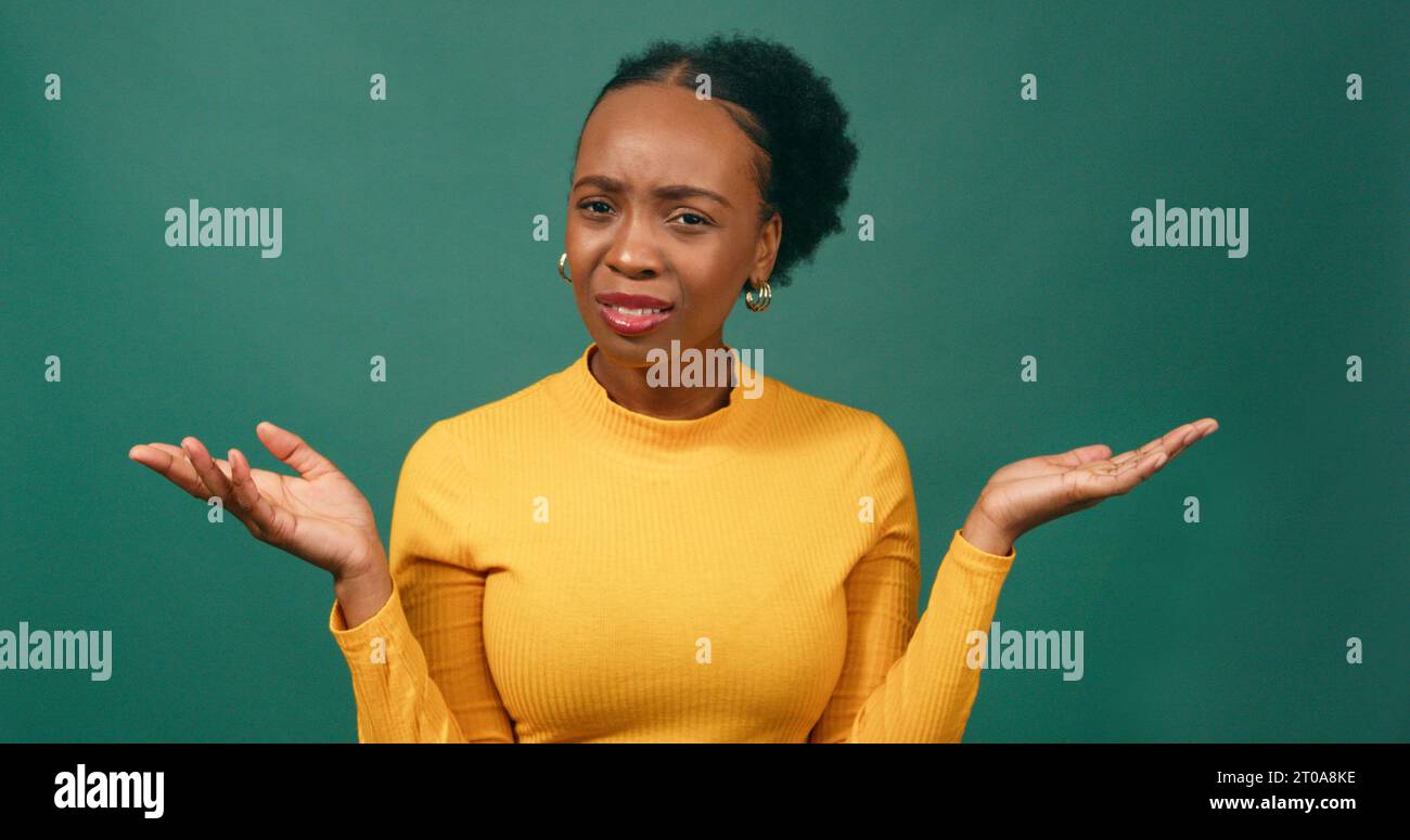 Shocked woman holds palms up in disbelief, green studio background Stock Photo