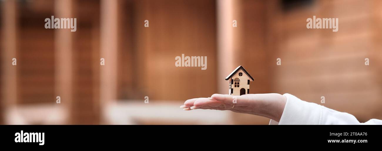 A small wooden house on a woman s hand against the background of a ...