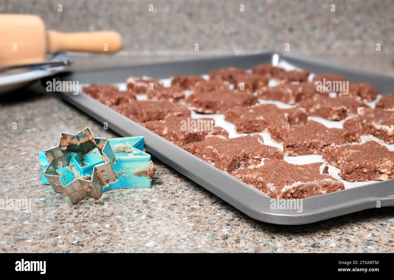 Gluten free chocolate cookies ready to be baked on kitchen counter. Raw star-shaped almond flour chocolate cookies on baking sheet. Swiss recipe Basle Stock Photo