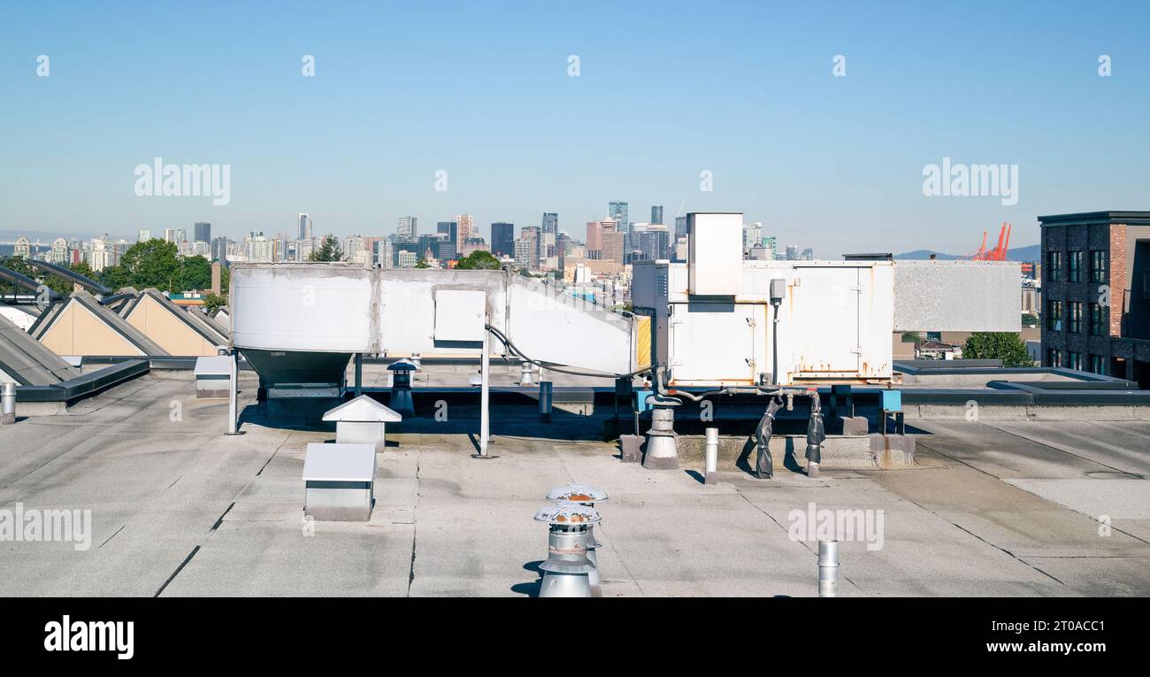 Hvac unit on flat roof with downtown skyline, vents and rooftop hatches