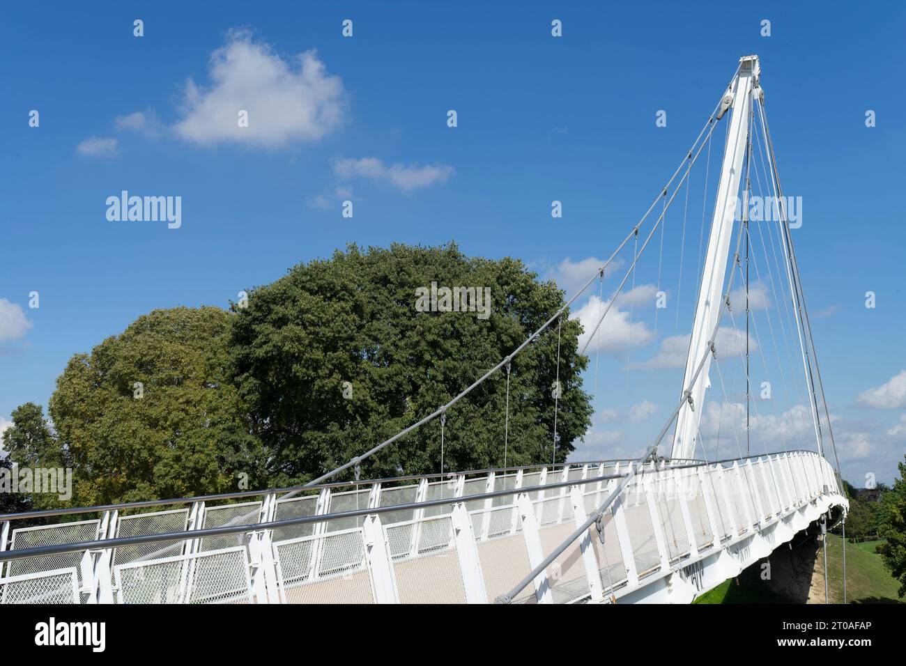 Walkway with modern white steel architecture suspended against the blue sky in the center crosses a public park in the urban of a European city Stock Photo
