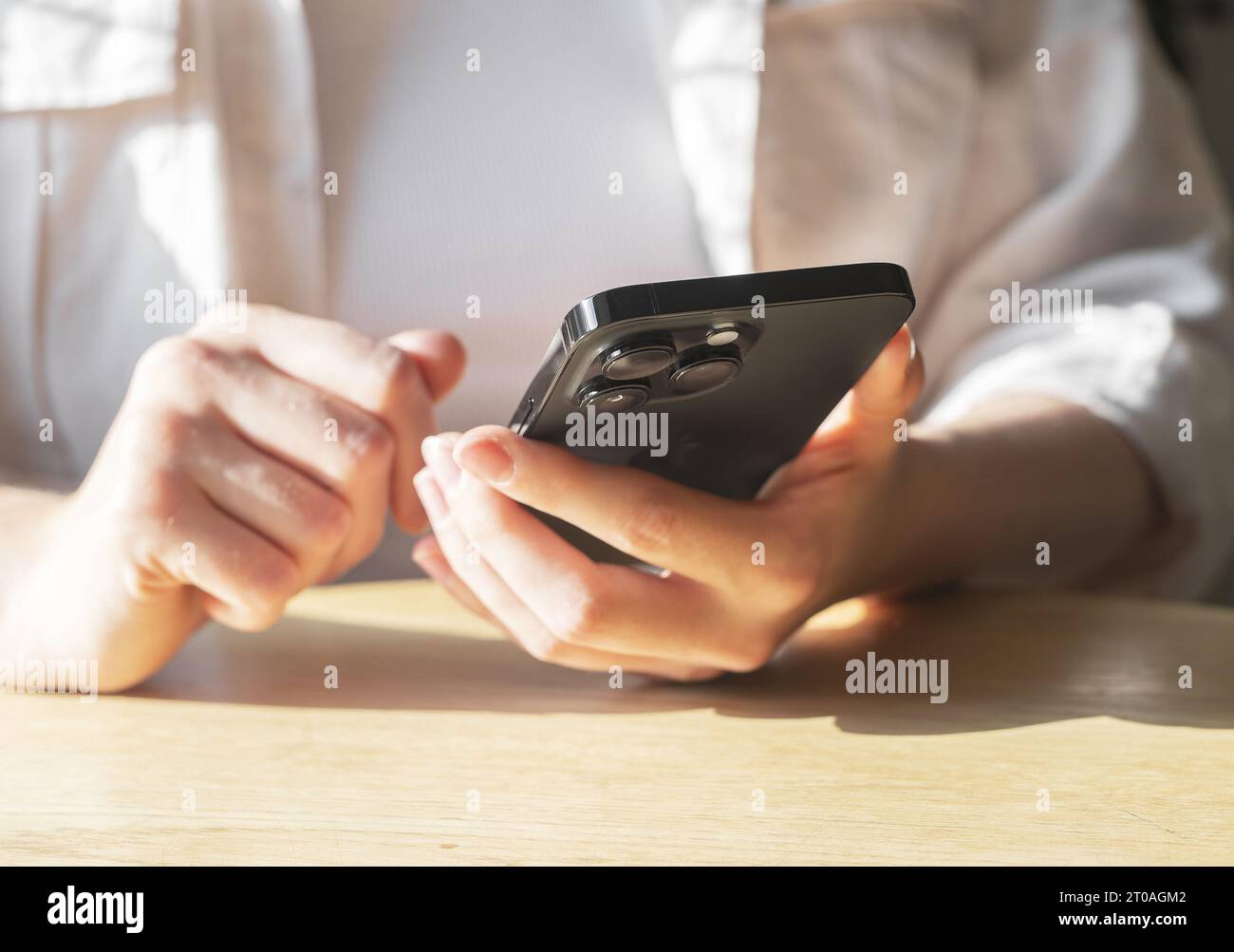 Berlin, Germany September 16 2023 Using mobile phone. Hands holding smartphone, reading news at table closeup Stock Photo