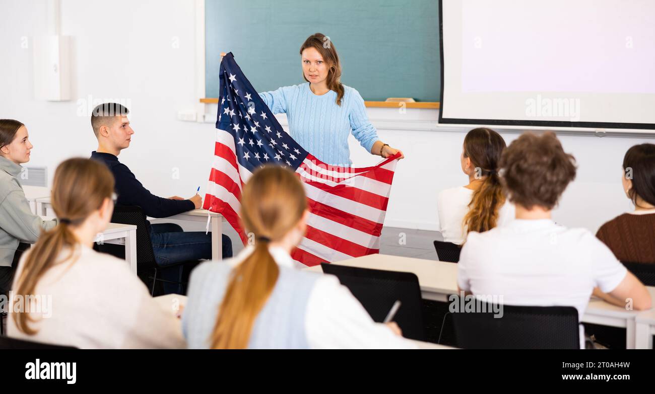 Geography lesson in school class - teacher talks about United States of America, holding flag in his hands Stock Photo