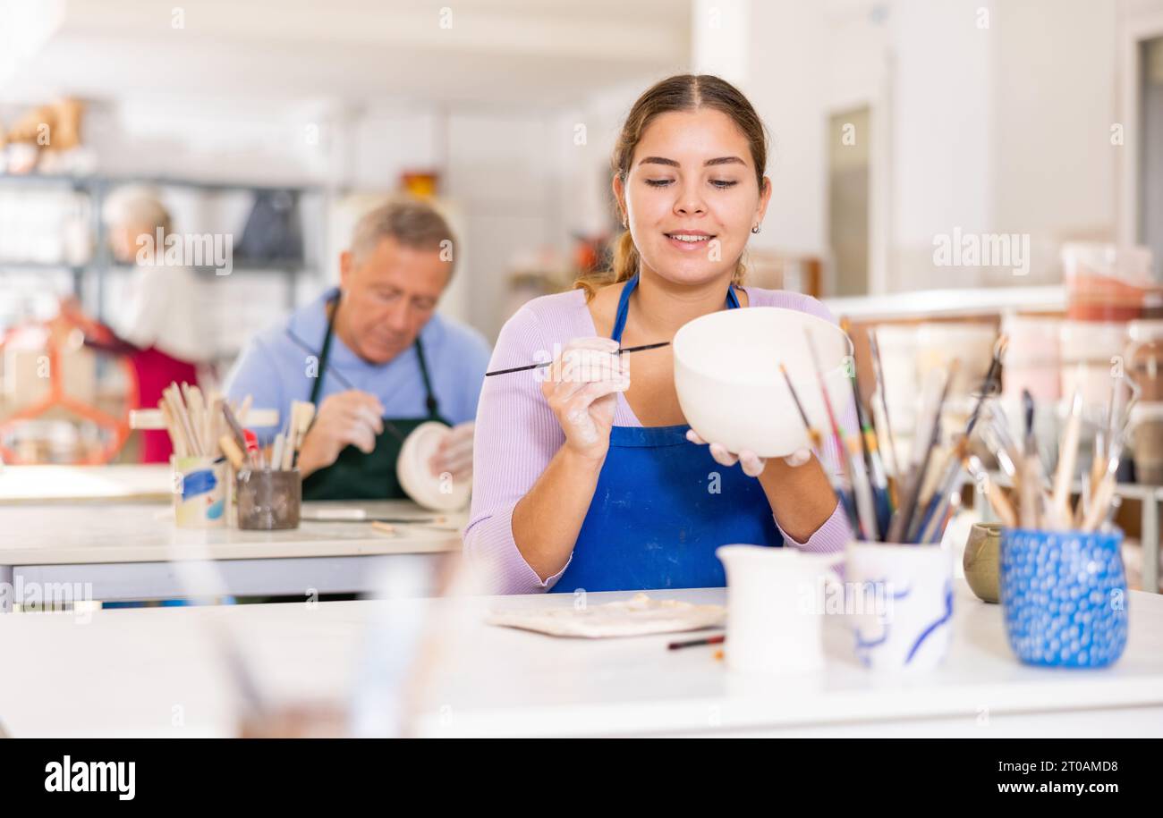 Woman learning to paint pottery at pottery class Stock Photo - Alamy