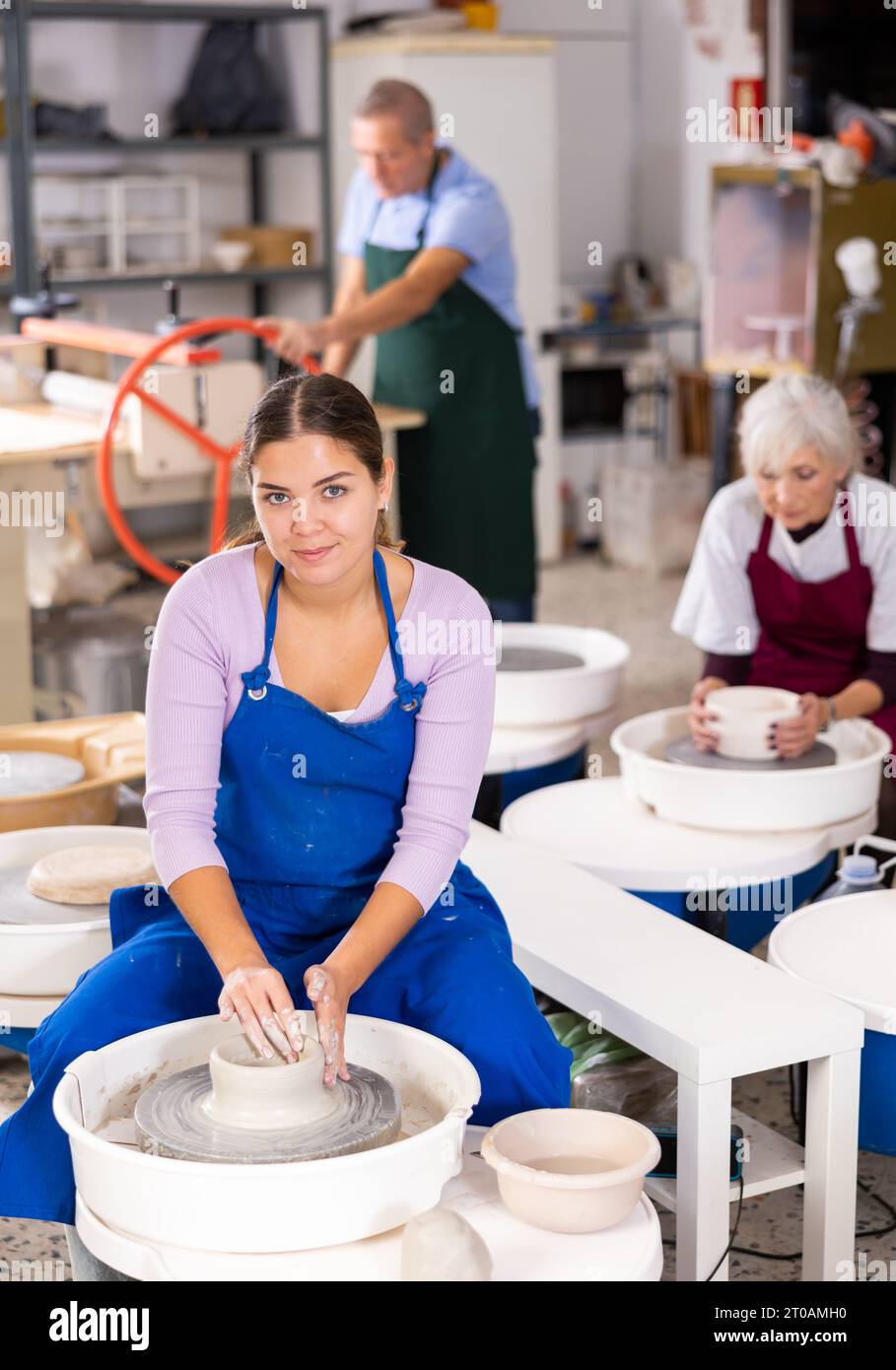 Female positive artisan in ceramics workshop with pottery wheel and ...