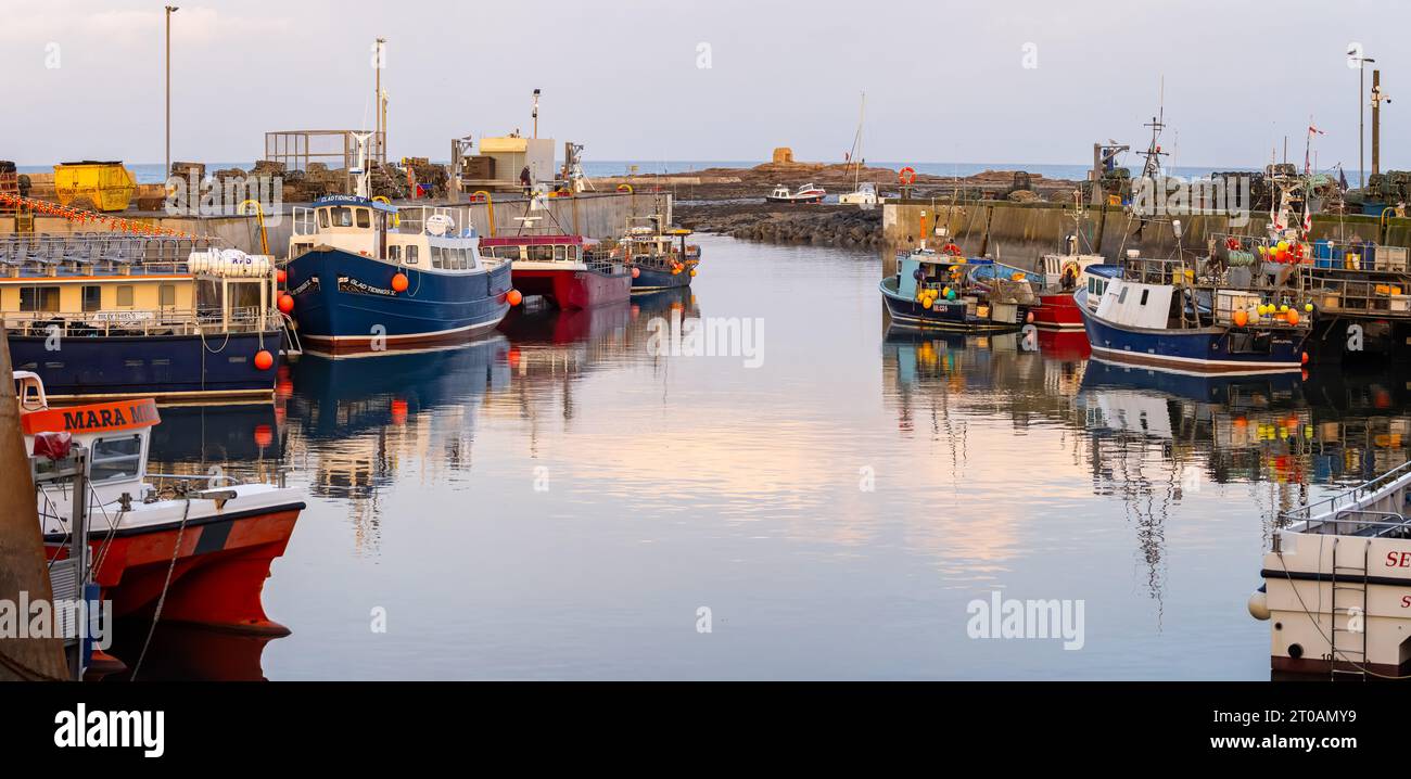 Fishing vessels moored in Seahouses harbour at sunset in Seahouses, Northumberland, UK on 25 September 2023 Stock Photo