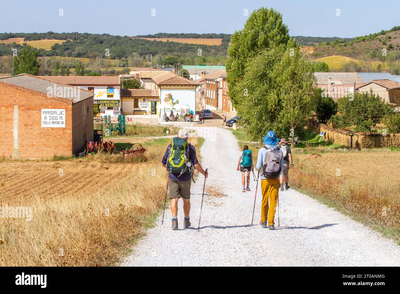 Pilgrims backpacking walking the long distance Spanish Camino de Santiago, the way of St James pilgrimage route approaching Calzadilla  de la Cueza Stock Photo