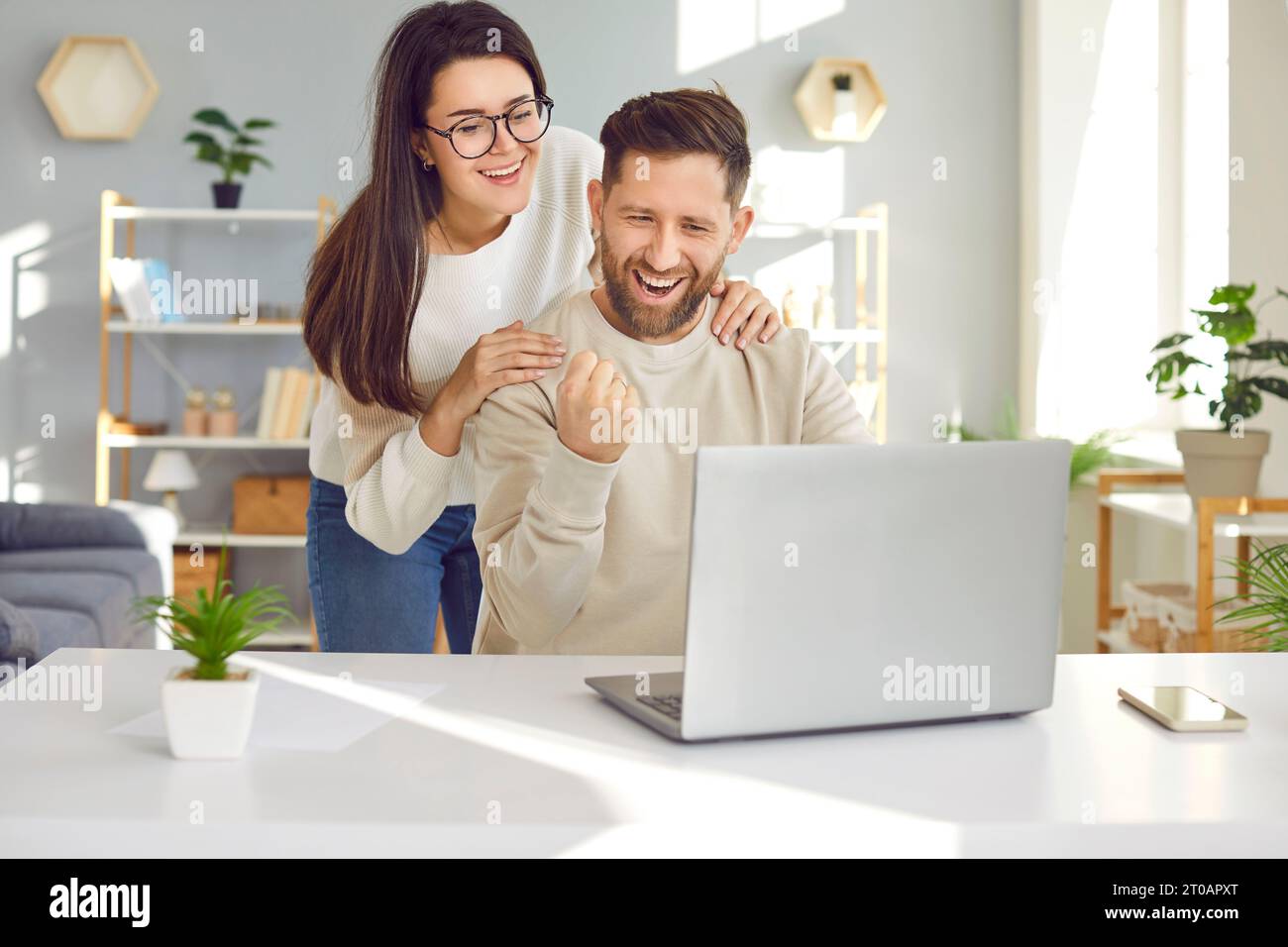 Cheerful young couple using laptop computer at home Stock Photo