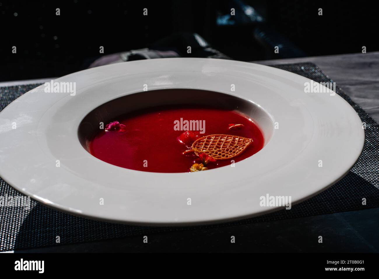 The red fruit , watermelon cold soup is poured into a light ceramic plate. Dishes stand on a light background. Stock Photo