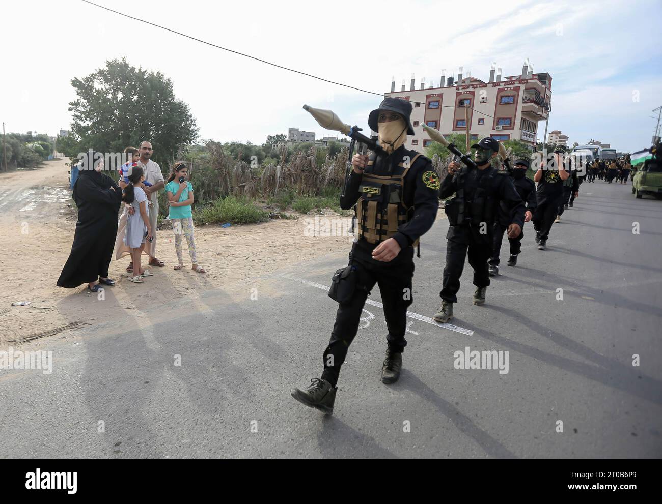 A Palestinian family watches members of the Al-Quds Brigades, the military wing of the Islamic Jihad movement, participate in an anti-Israel military parade on the occasion of the 36th anniversary of the founding of the movement in Gaza City. Stock Photo