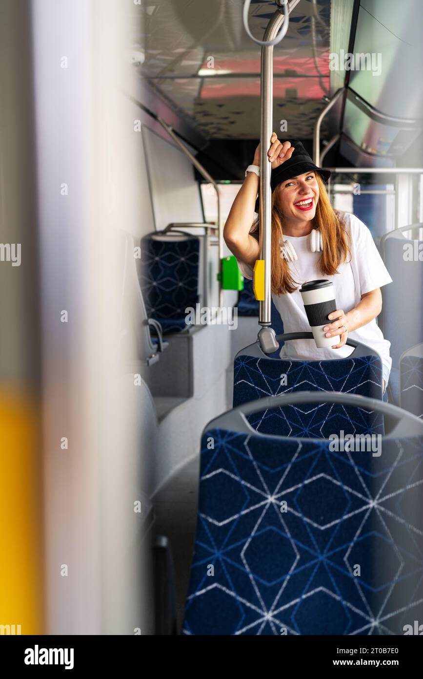 City lifestyle photography. Young joyful woman laughing while traveling city bus. Urban life and youth. Public transportation. Stock Photo