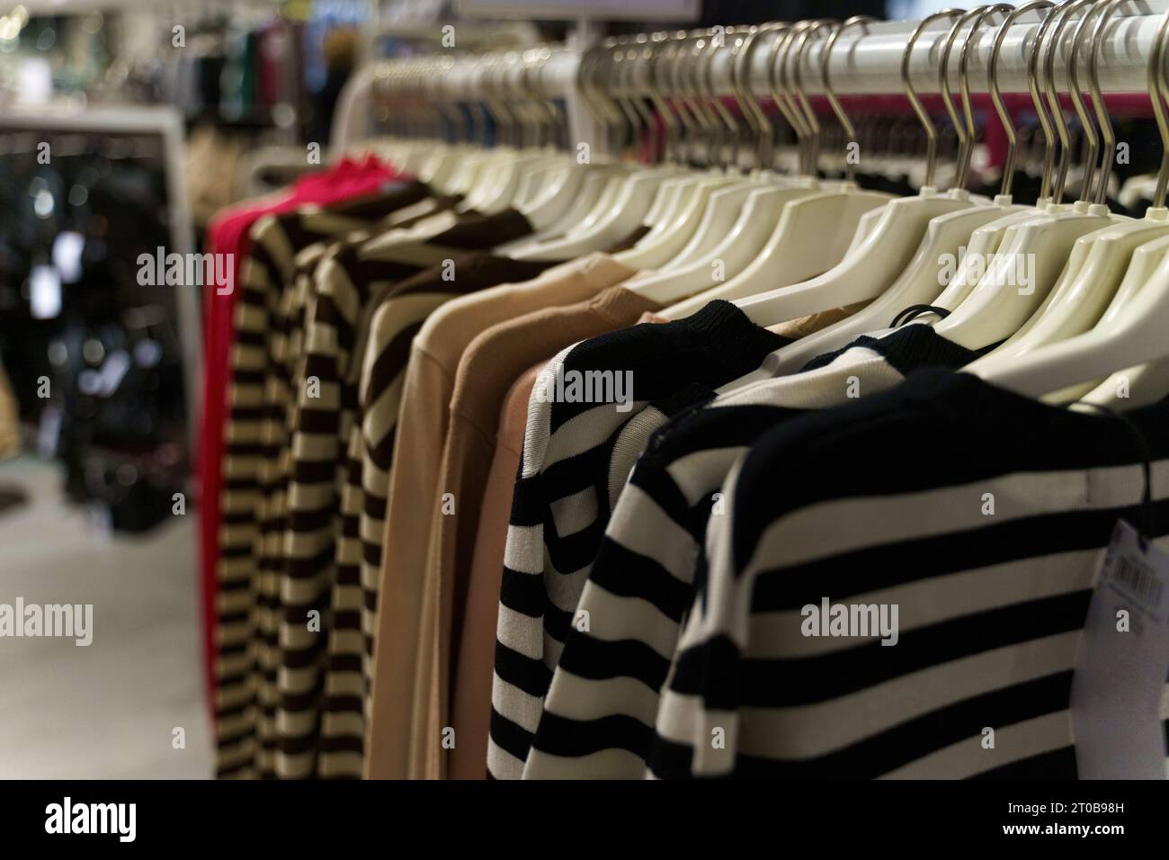 Women's jumpers hang on hangers in a clothing store. Close-up, background. Stock Photo