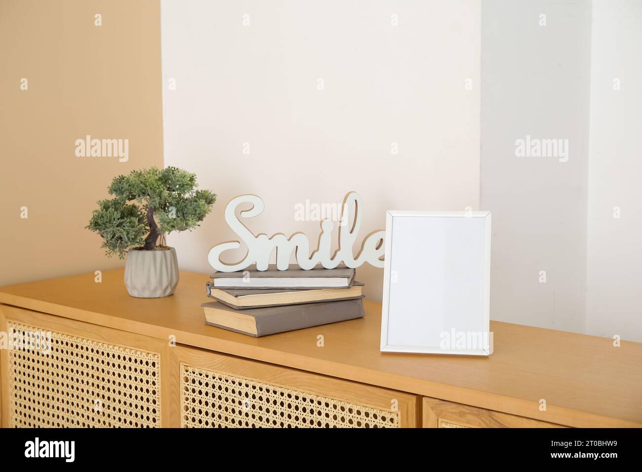 Blank frame, books and decorative tree in pot on wooden sideboard Stock ...
