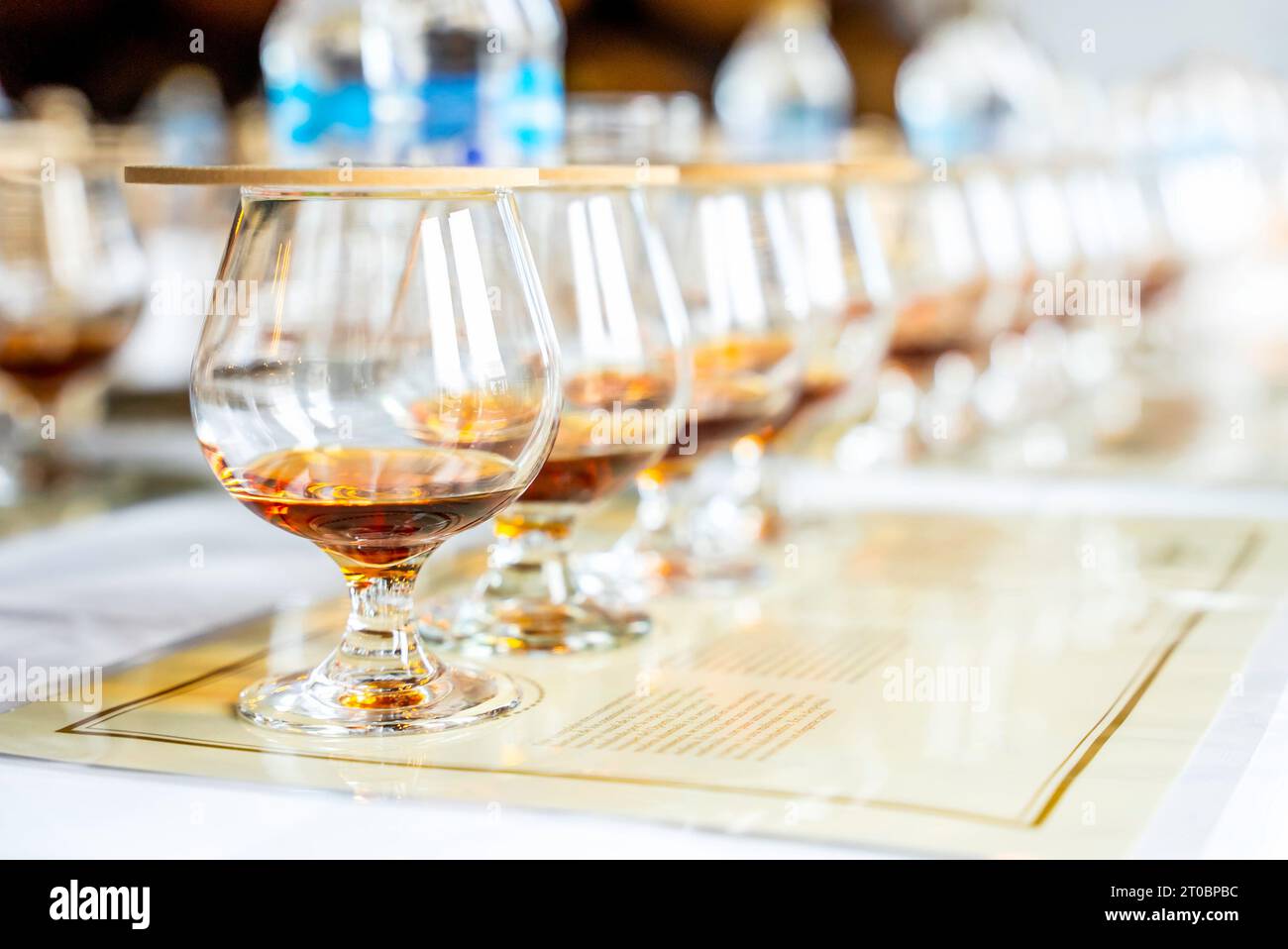 Close up of row transparent covered drinking glasses with rum on the tasting placemats with copy space. Stock Photo