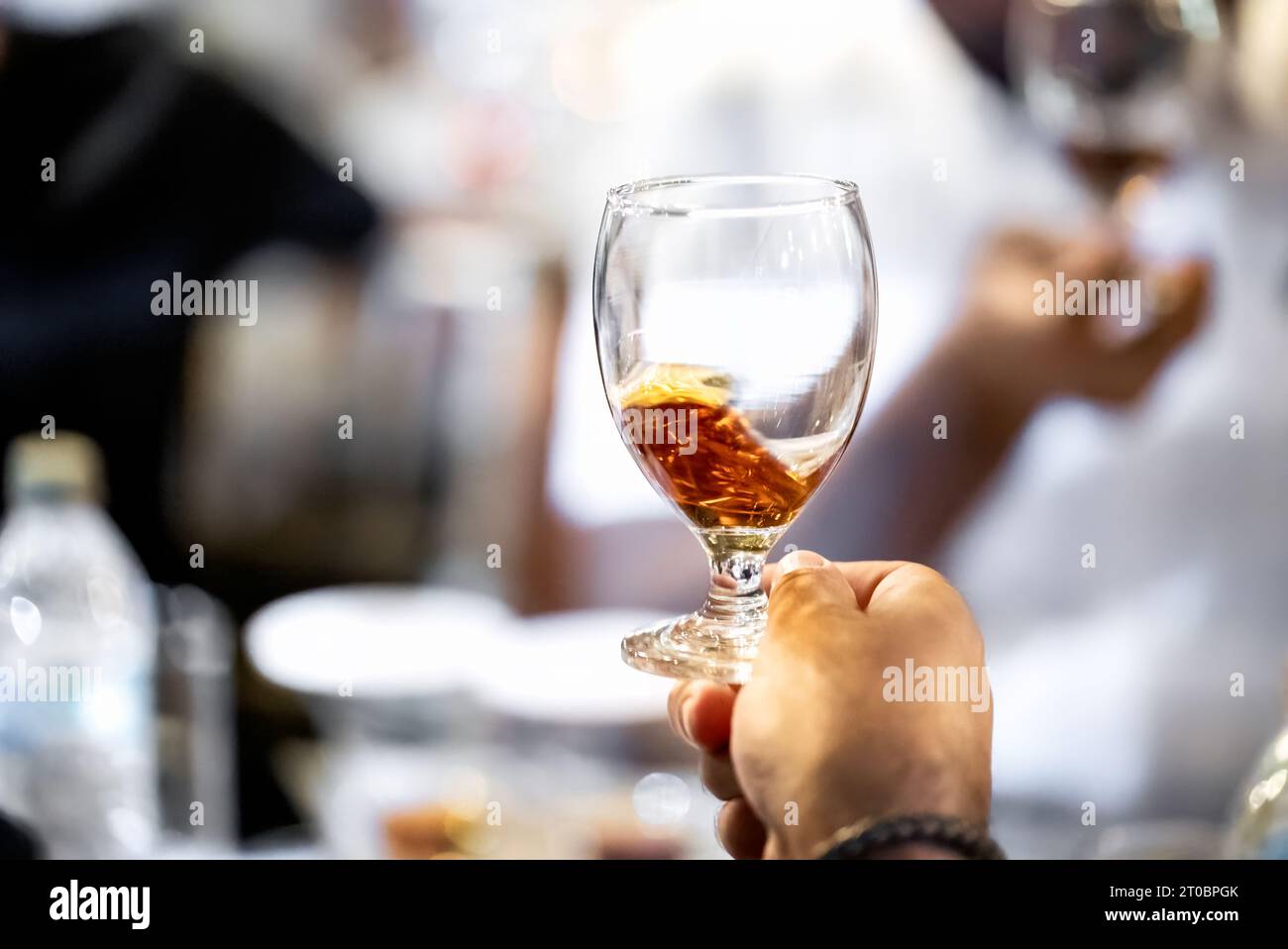 Close up of copa glass with splashing rum in a male hand. Best room tasting liquors events Stock Photo