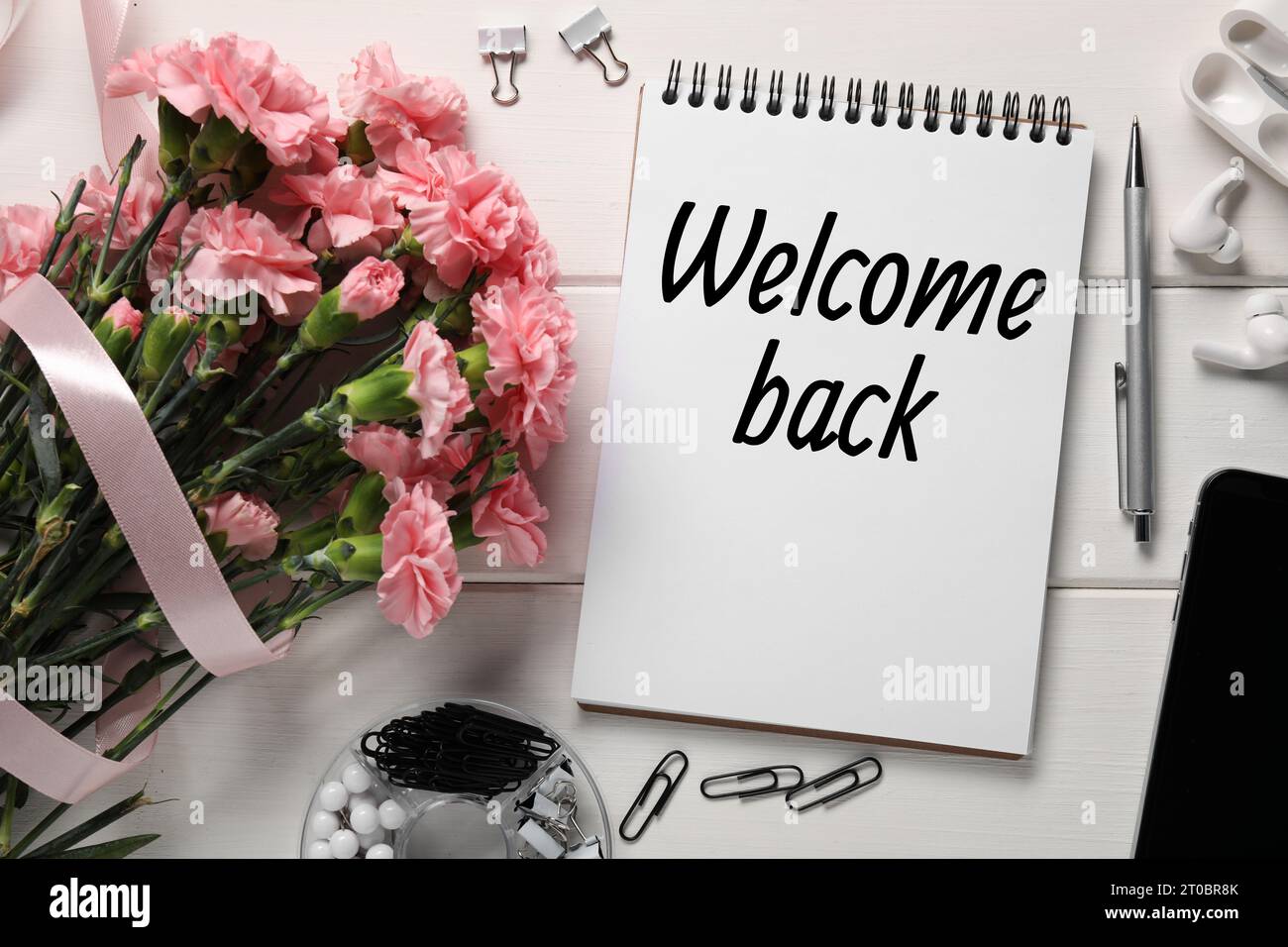 Notebook with phrase Welcome Back, bouquet of flowers and stationery on ...