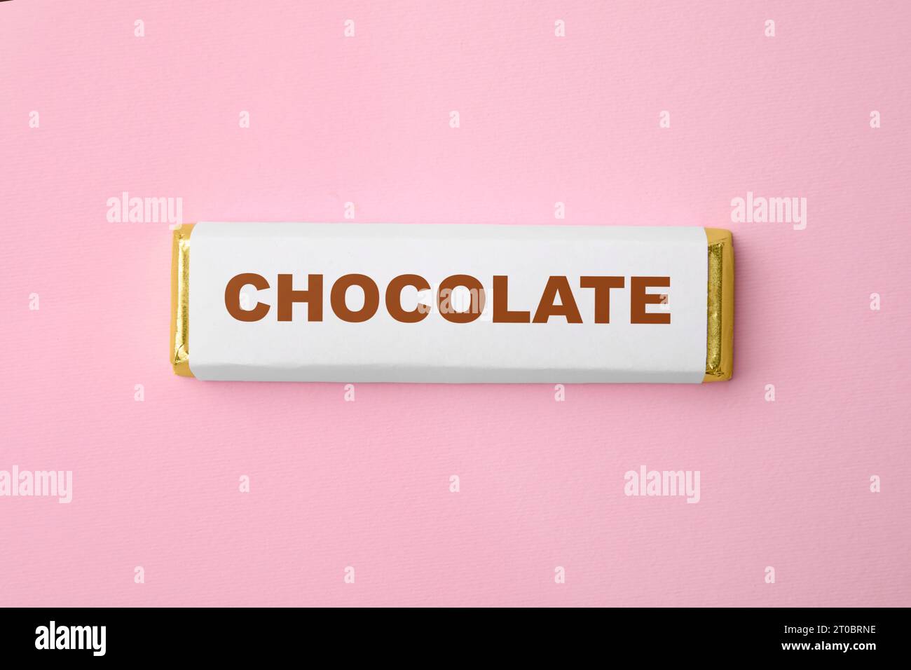 One chocolate bar in packaging on pink background, top view Stock Photo