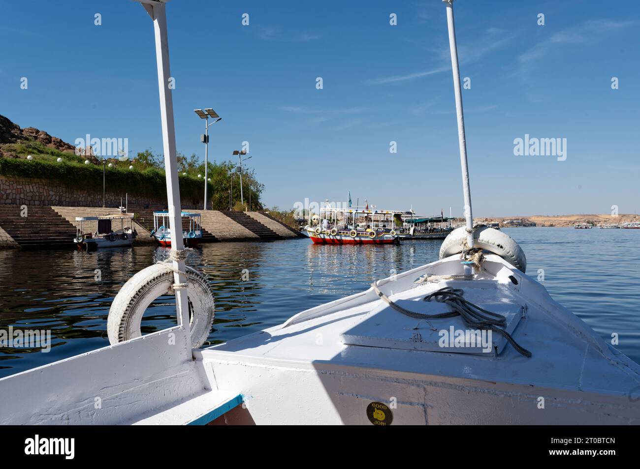 photo taken from a boat showcasing the dock bay of the philae temple, featuring a vibrant traditional boat. Stock Photo